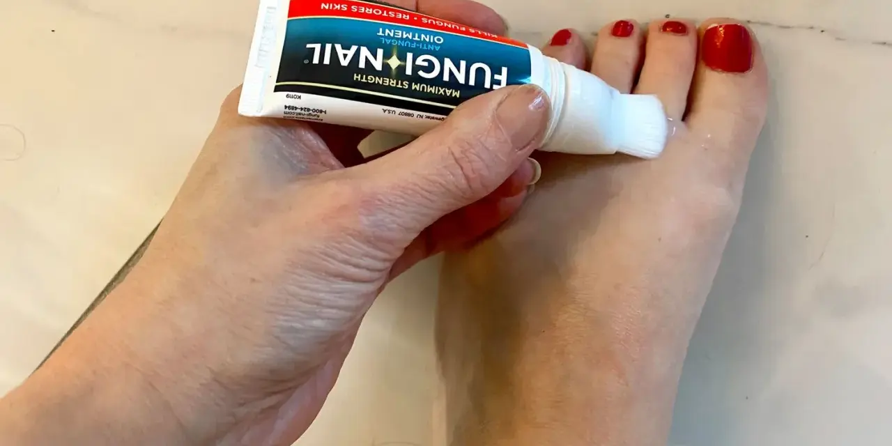 Dłoń aplikuje maść Fungi Nail na paznokcie u stóp. Preparat, podobny do żelu, zawiera metronidazol, pomagając w walce z grzybicą.