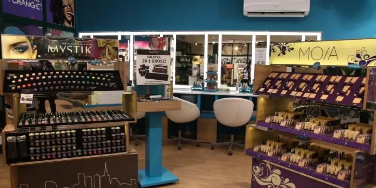 Wnętrze sklepu z kosmetykami kontigo. Rzędy kolorowych paletek cieni do powiek i szminek na półkach.