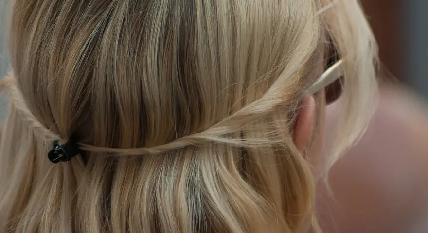 Piaskowy blond włosów spięty warkoczem z tyłu głowy. Delikatne pasma opadają na ramiona.
