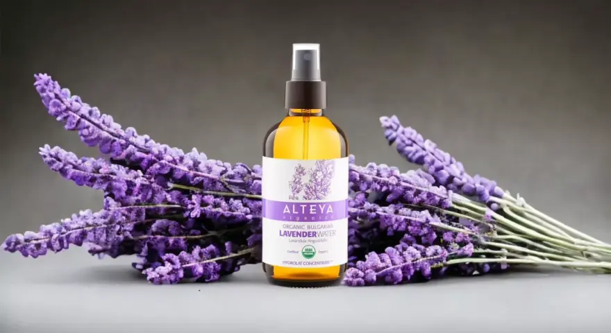 Butelka z organiczną wodą lawendową Alteya Organics otoczona bukietami fioletowej lawendy.