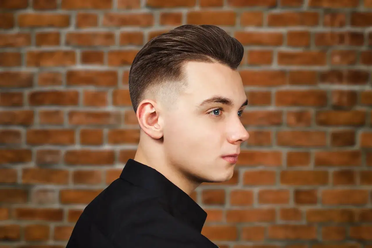Młody mężczyzna z modną fryzurą, która dodaje mu uroku. Stylowe fryzury męskie, które odmładzają, to klucz do świeżego wyglądu.
